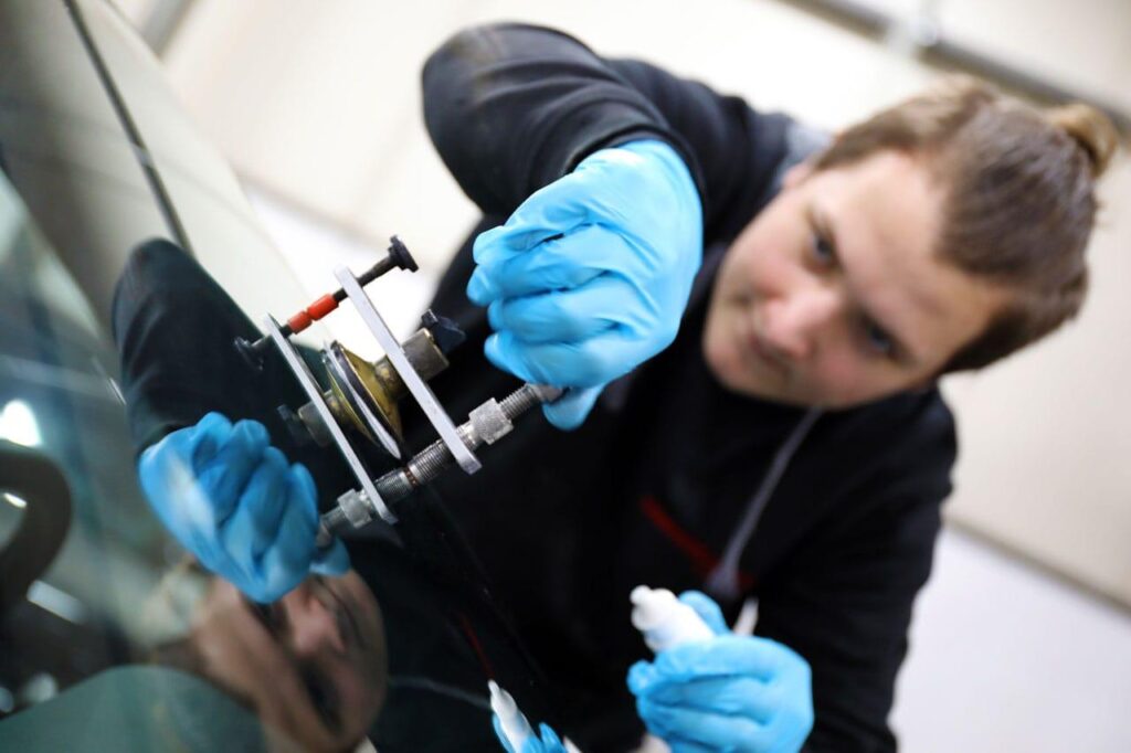 Technicien réparant un impact sur un pare-brise avec une résine d'injection